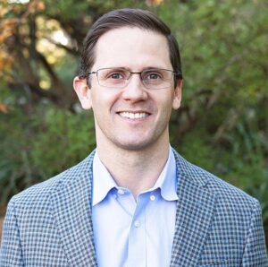 Portrait of an endodontist at Maupin Endodontics in Lubbock, Texas, wearing glasses and a professional jacket outdoors